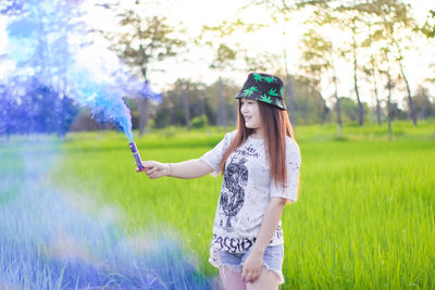 Woman holding distress flare while standing on land