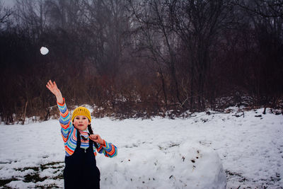 Portrait of smiling girl standing against trees during winter