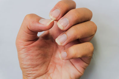 Close-up of woman holding hands over white background