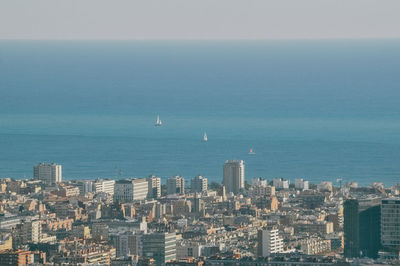 Aerial view of cityscape by sea against clear sky