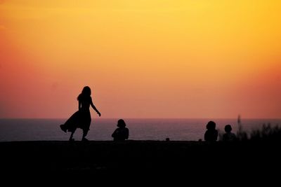 Silhouette people at beach against sky during sunset