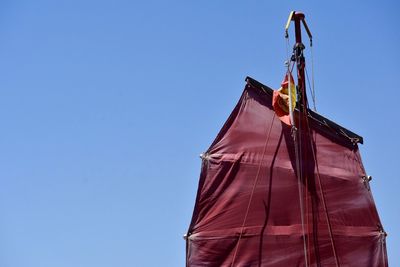 Low angle view of flags against clear blue sky