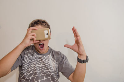 Boy watching virtual reality while screaming against gray background