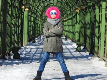 Portrait of girl wearing sunglasses while standing on snow covered footpath