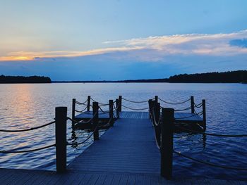 Pier over lake against sky during sunset