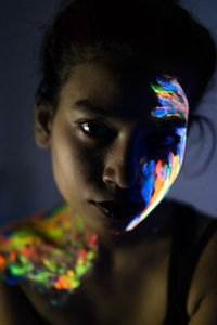 Close-up of woman with glowing paint on face
