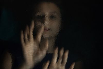 Close-up of woman holding hair over black background