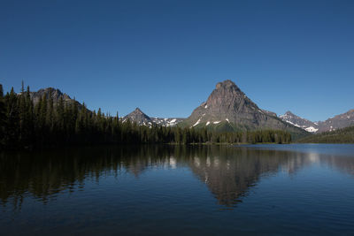Scenic view of lake and mountains against clear blue sky