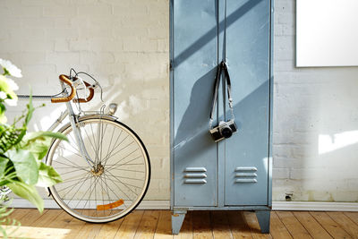 Bicycle by locker against wall at home