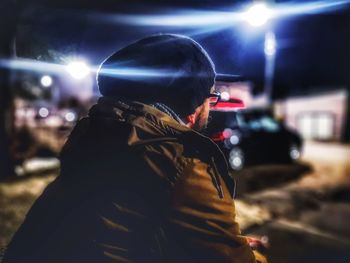 Rear view of man on illuminated street at night