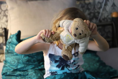 Close-up of girl holding bear toy at home