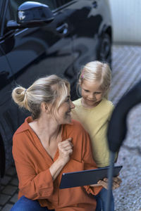 Happy mother showing tablet pc to daughter in front yard