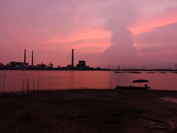 Smoke emitting from factory against sky during sunset