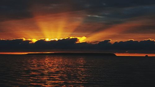 Scenic view of sea against dramatic sky during sunset