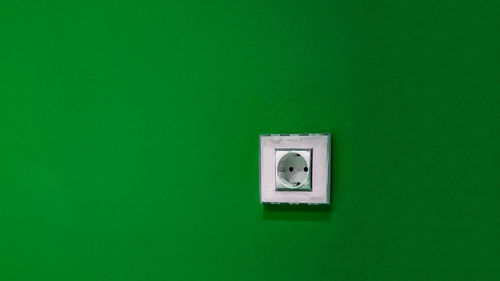 Close-up of electric lamp on green wall