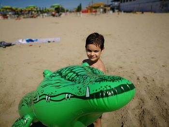 Portrait of happy boy with toy on beach