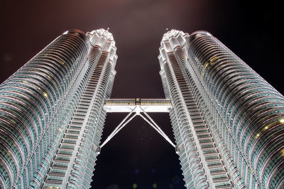 Low angle view of petronas towers against sky in city at night