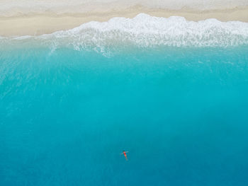 Aerial view of woman in red bikini swims in the sea