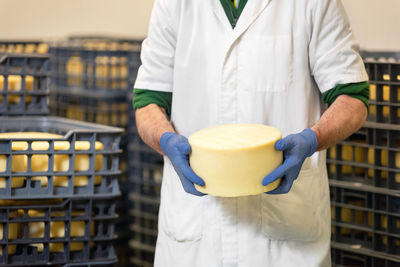 Midsection of man holding cheese at factory