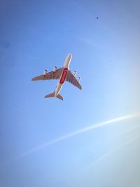 Low angle view of airplane flying against clear blue sky