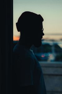 Side view portrait of young man looking away against sky during sunset
