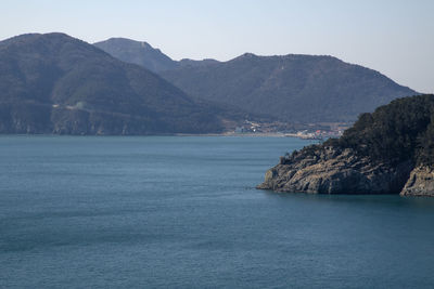 Scenic view of sea and mountains against clear sky