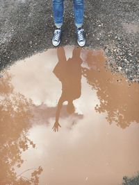 Low section of man standing on puddle