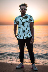 Portrait of young woman standing at beach during sunset