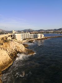 Buildings by sea against clear sky