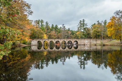 Arch bridge over lake against sky during autumn