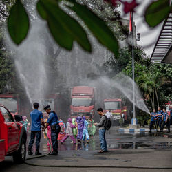 Rear view of people standing on wet street in rainy season