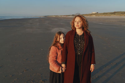 Portrait of woman with daughter standing on beach