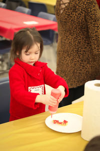 Cute girl holding ketchup bottle in restaurant