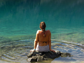 Full length of shirtless man sitting in sea