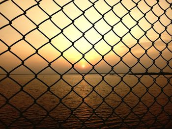 Scenic view of sunset seen through chainlink fence