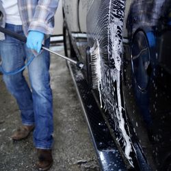 Midsection of man cleaning car with equipment in garage