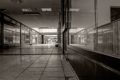 Empty footpath amidst buildings seen through glass window