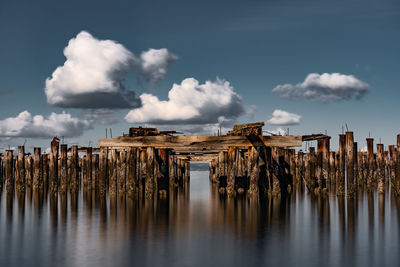 Panoramic view of wooden posts by sea against sky