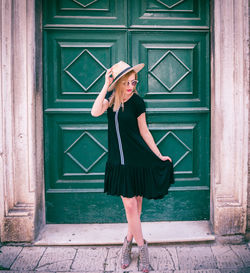 Young woman standing against closed door