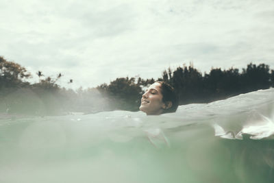 Woman swimming in sea against cloudy sky