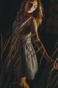 Woman standing by plants at night