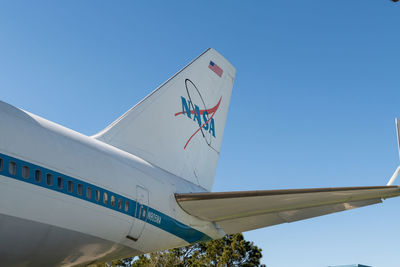 Low angle view of airplane against clear blue sky