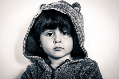 Portrait of cute boy wearing hooded shirt against wall