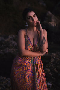 Portrait of young woman standing against blurred background