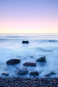 Romantic morning at sea. big boulder in smooth wavy sea. long exposure for smooth dreamy water level