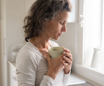 Close-up of woman drinking coffee at home