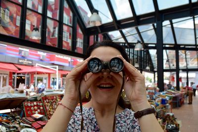 Woman looking through binoculars in market