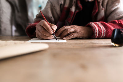 Midsection of senior man writing on paper