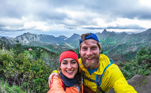 Portrait of happy friends against mountains