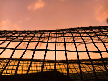 Low angle view of silhouette fence against sky during sunset